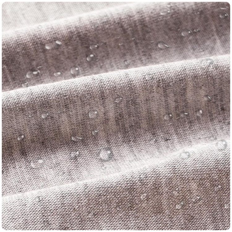 Zbliżenie na wodoodporny materiał majtek menstruacyjnych z widocznymi kroplami wody.