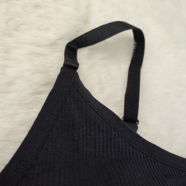 Zbliżenie na plastikowy regulator ramiączka w czarnym biustonoszu prążkowanym.