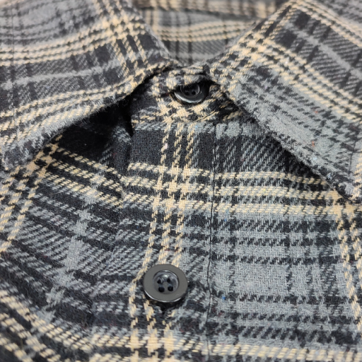 Zbliżenie na kołnierzyk i zapięcie na guziki koszuli flanelowej w kratę.