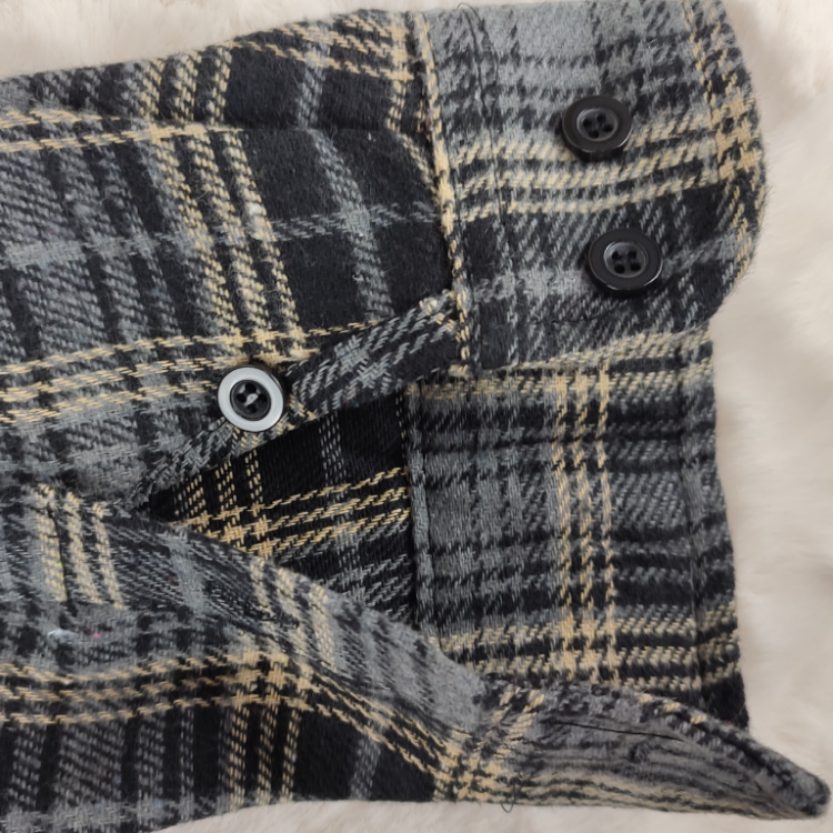 Widok otwartego mankietu z guzikami w koszuli flanelowej w kratę.