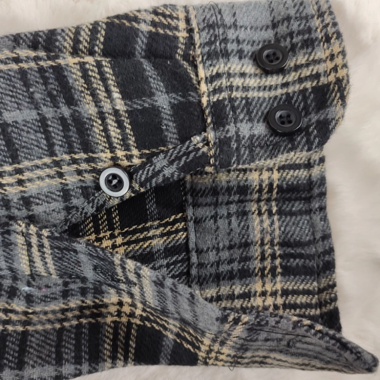 Widok otwartego mankietu z guzikami w koszuli flanelowej w kratę.