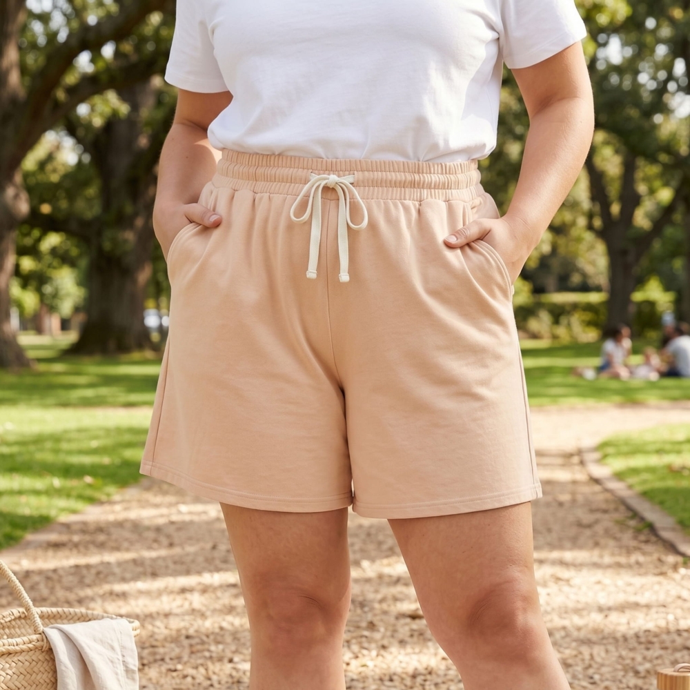 Modelka plus size w beżowych szortach damskich bawełnianych podczas spaceru w słonecznym parku.