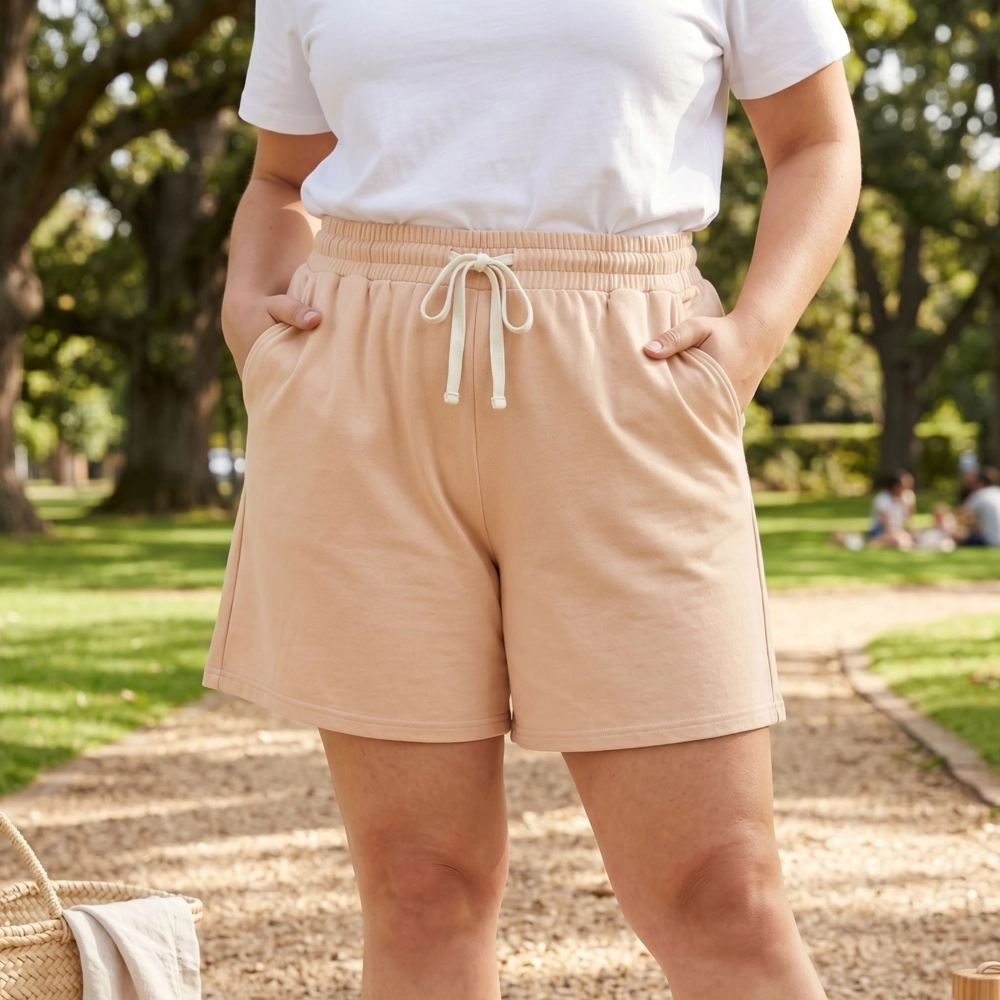 Modelka plus size w beżowych szortach damskich bawełnianych podczas spaceru w słonecznym parku.
