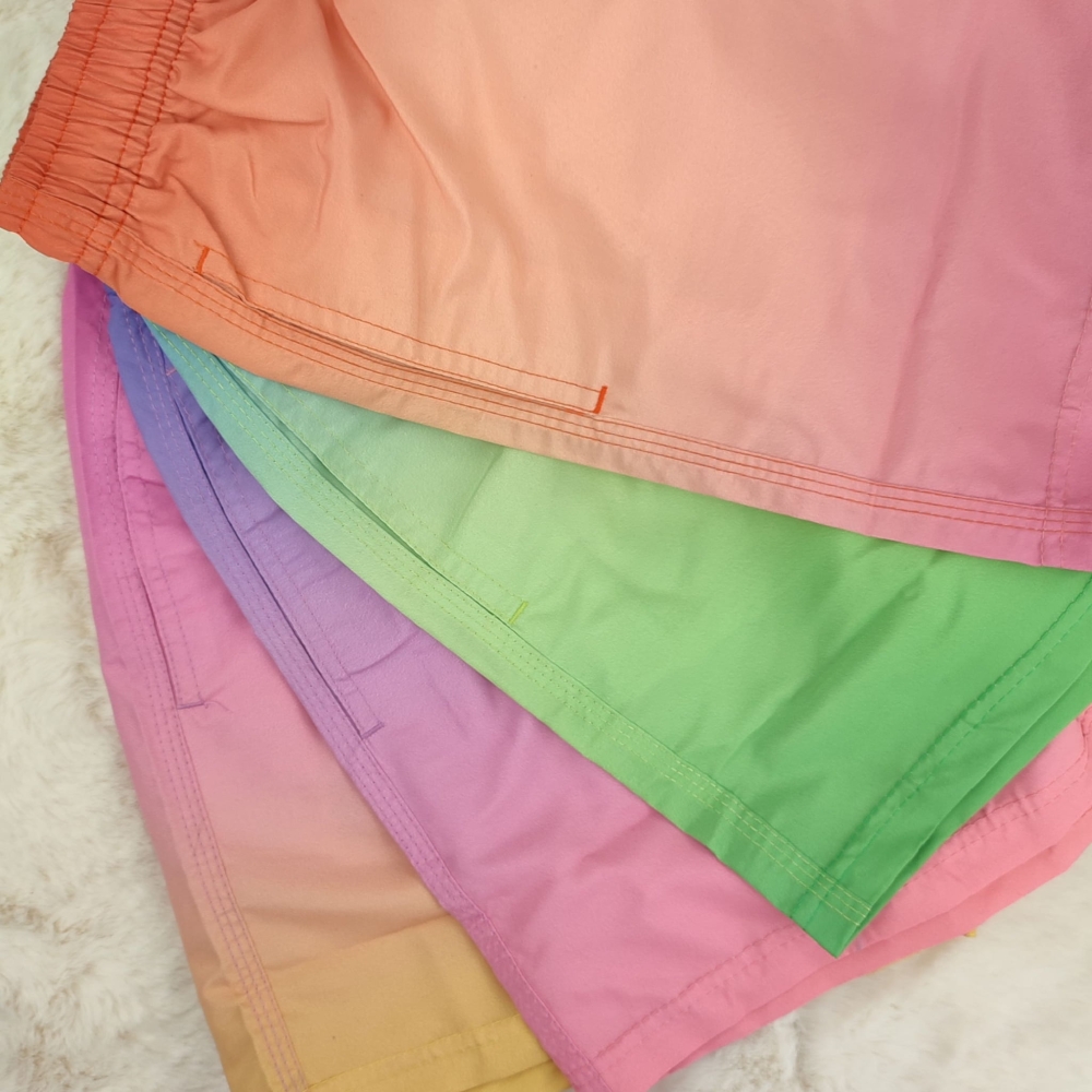 Zbliżenie na dolne wykończenie i proste nogawki sportowych szortów kąpielowych w wariantach kolorystycznych ombre.