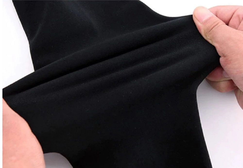 Legginsy ocieplane damskie z futerkiem czarne – rozciąganie elastycznego materiału w dłoniach
